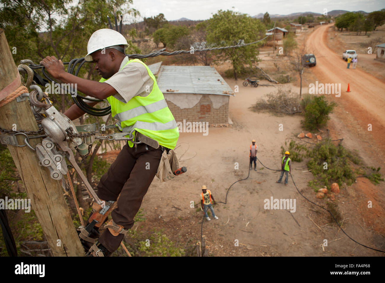 Workers string new power cables in a rural village near Dodoma, Tanzania, East Africa. Stock Photo