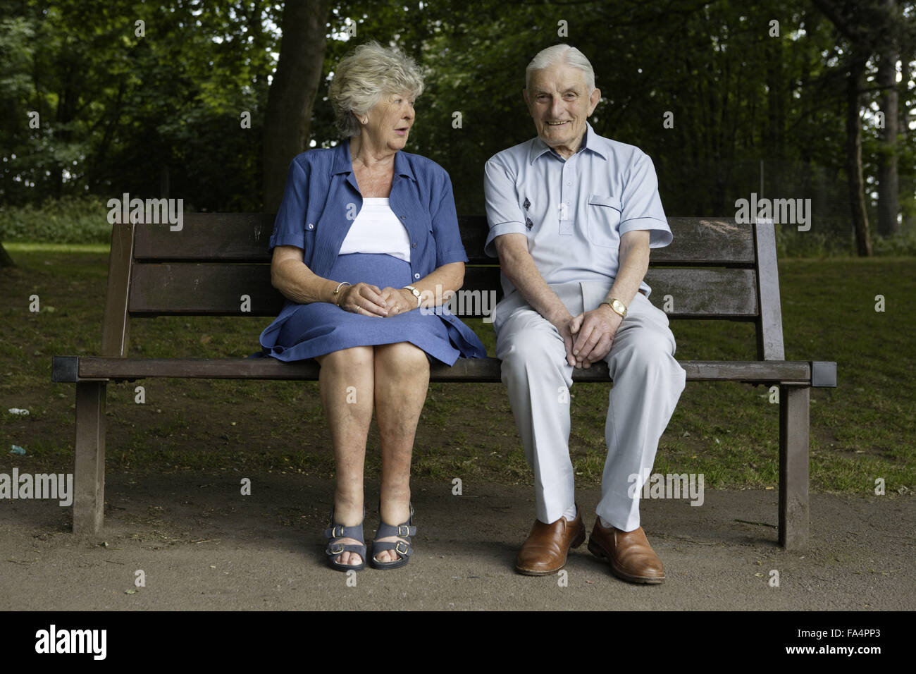 Older couple sitting on a bench in the park Stock Photo - Alamy