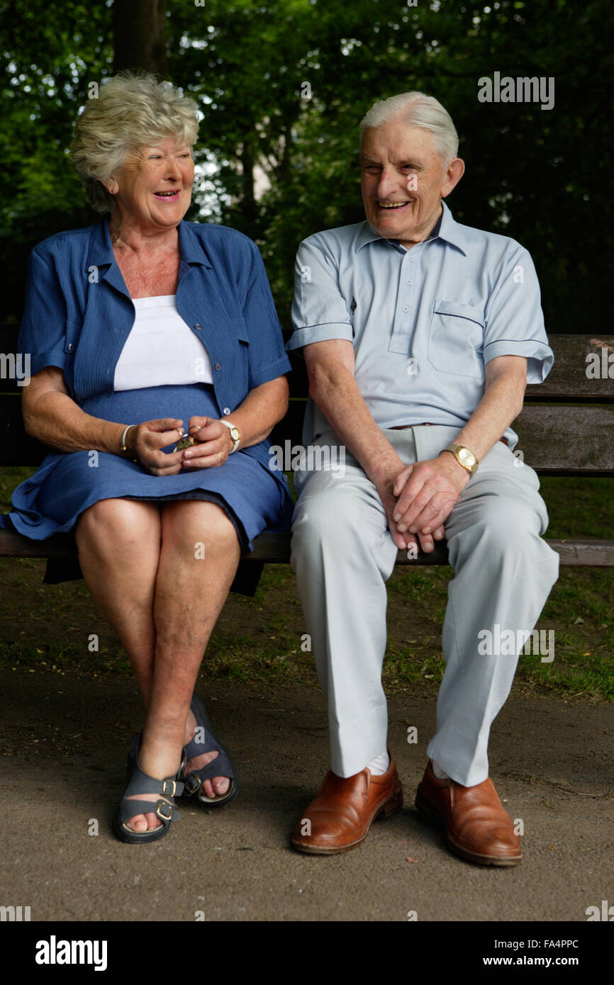 Older couple sitting on a bench in the park chatting, Stock Photo