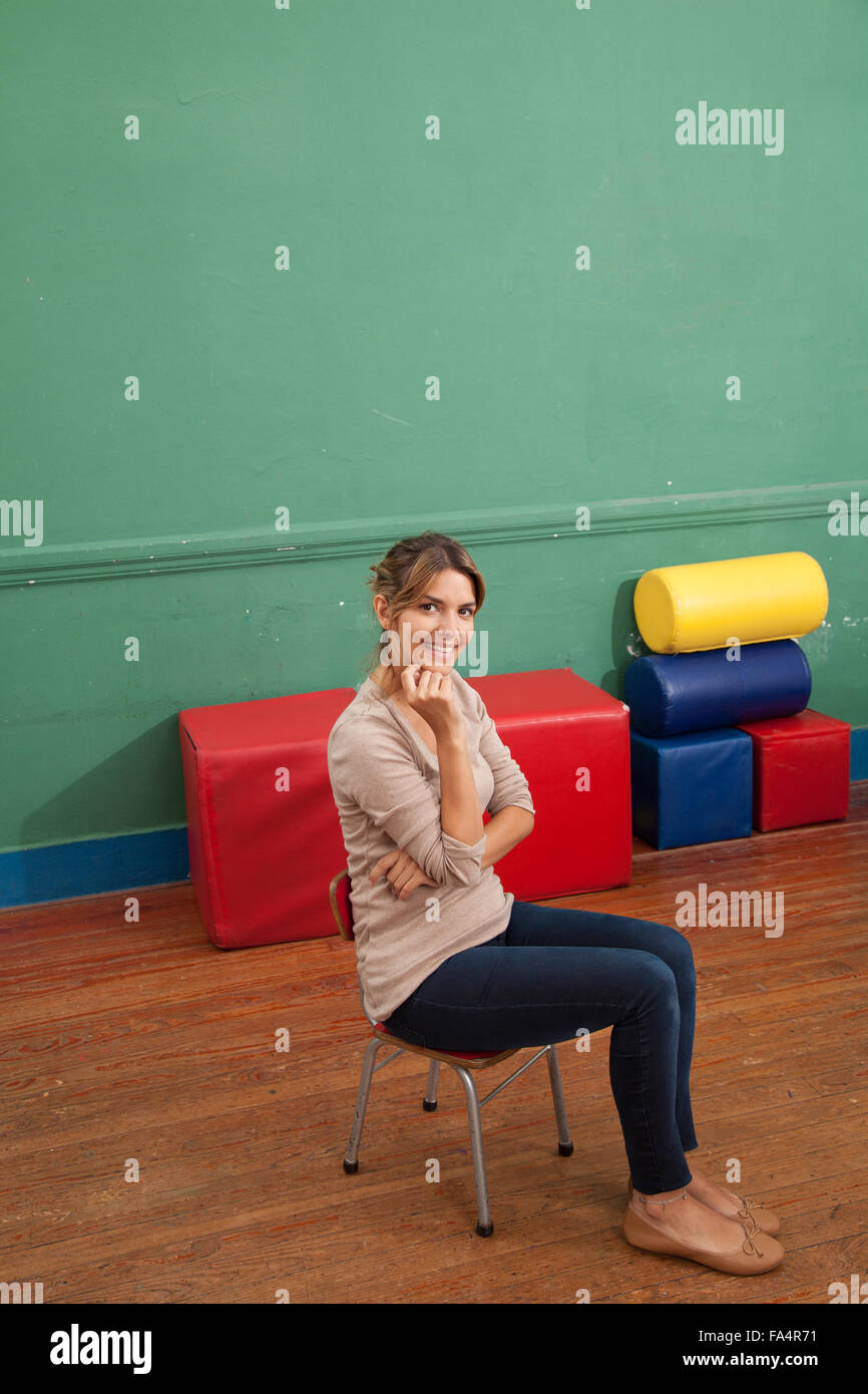 Teacher sitting and smiling at school Stock Photo - Alamy