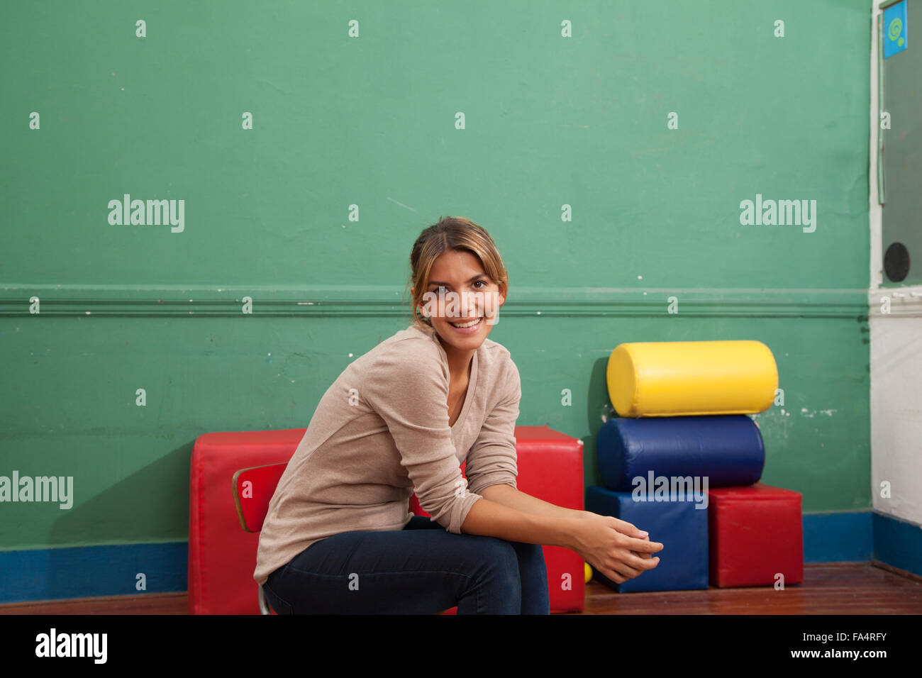Teacher sitting and smiling at school Stock Photo - Alamy