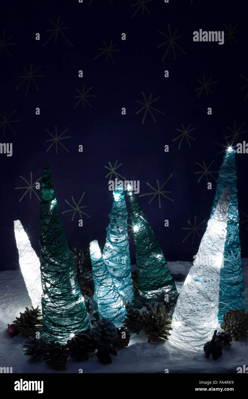 a vertical frontal view of some handmade illuminated trees in a snowed scene with space for a message Stock Photo