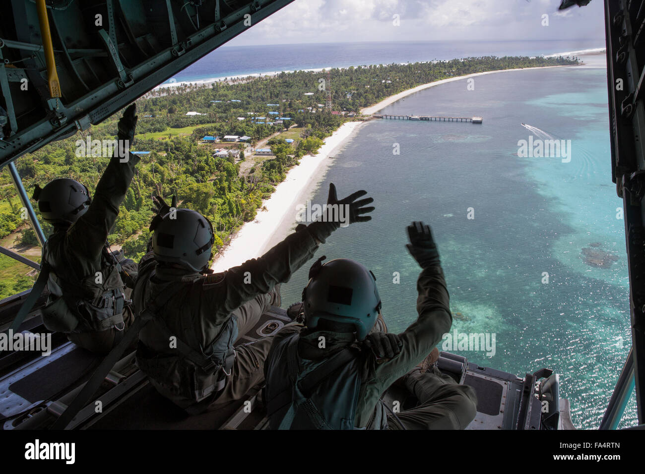 U.S. Air Force airmen wave from the back of their C-130 Hercules aircraft after air dropping gifts during Operation Christmas Drop December 11, 2015 in Kayangel, Republic of Palau. Operation Christmas Drop is the longest running Department of Defense humanitarian operation covering 56 remote Pacific islands. Stock Photo