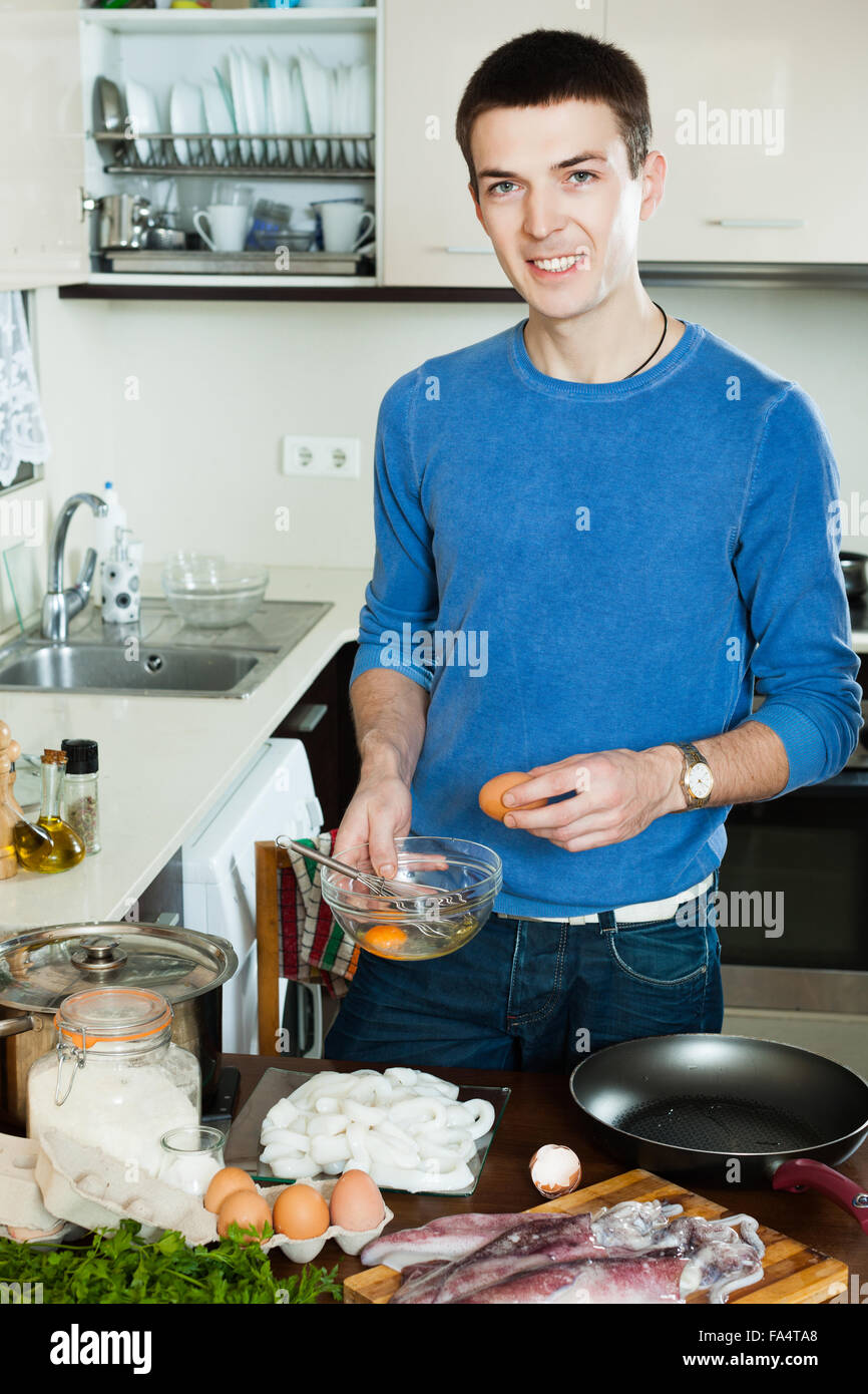 Smiling guy preparing batter for cooking calamari rings Stock Photo