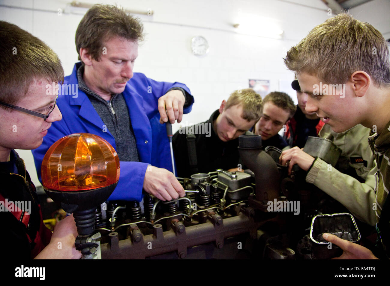 Practical education at a tractor. Master explains the engine of an agricultural machinery. Stock Photo