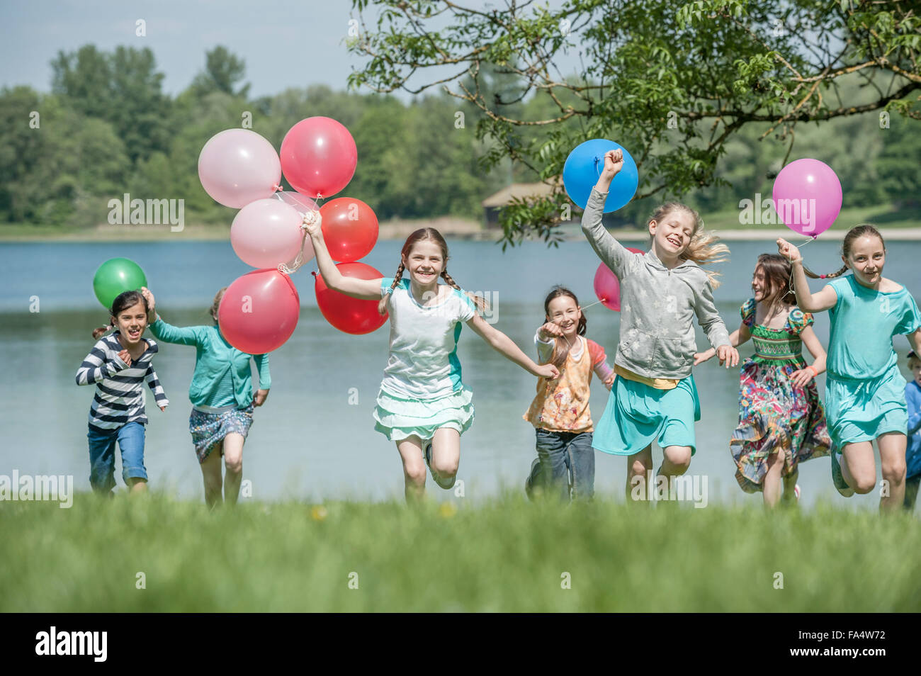 Children running in park with balloons, Munich, Bavaria, Germany Stock Photo