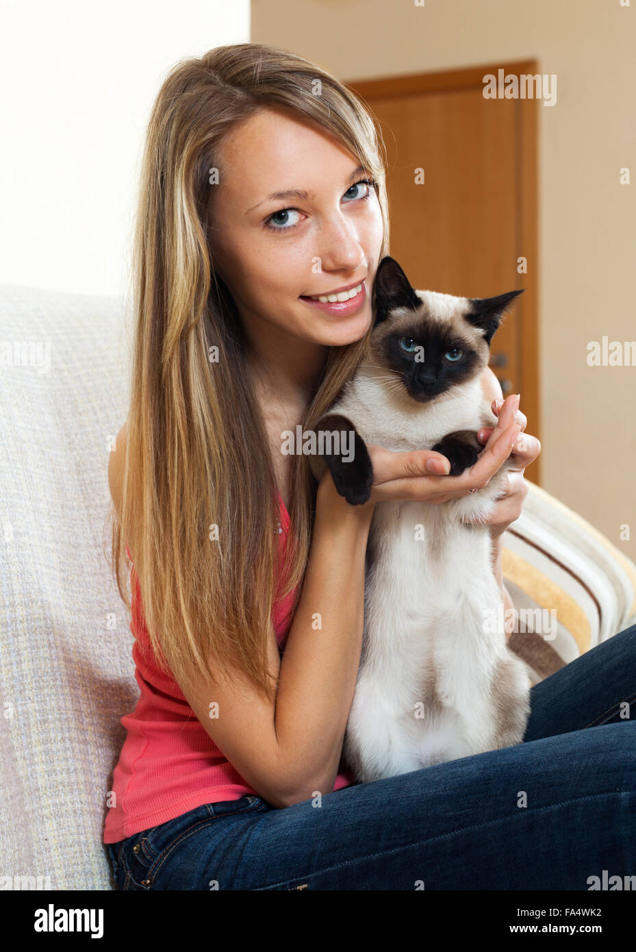 Smiling girl with a Siamese cat in her arms in the room Stock Photo Alamy