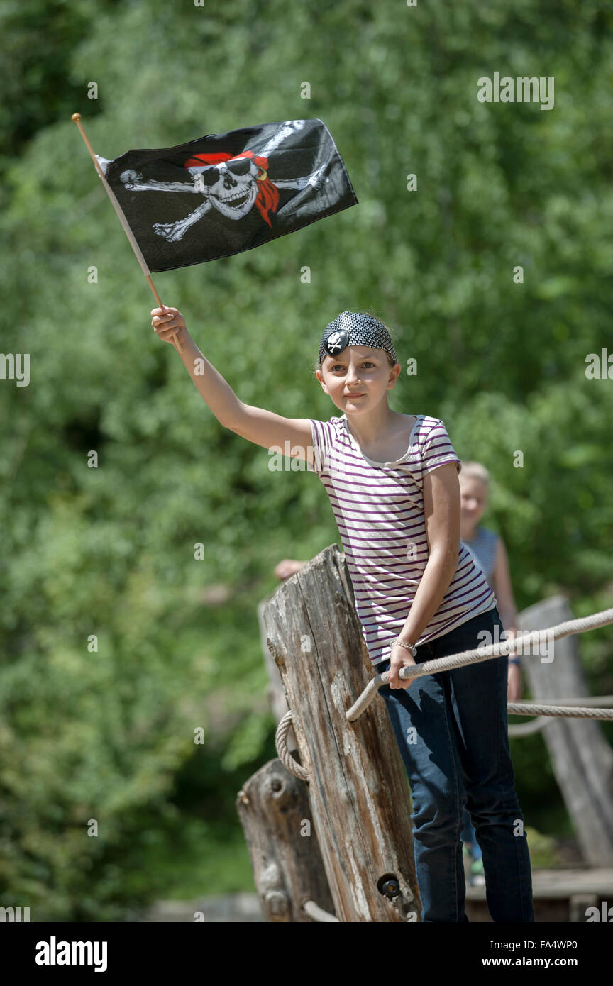 Girl standing on pirate ship and showing pirate flag in adventure playground, Bavaria, Germany