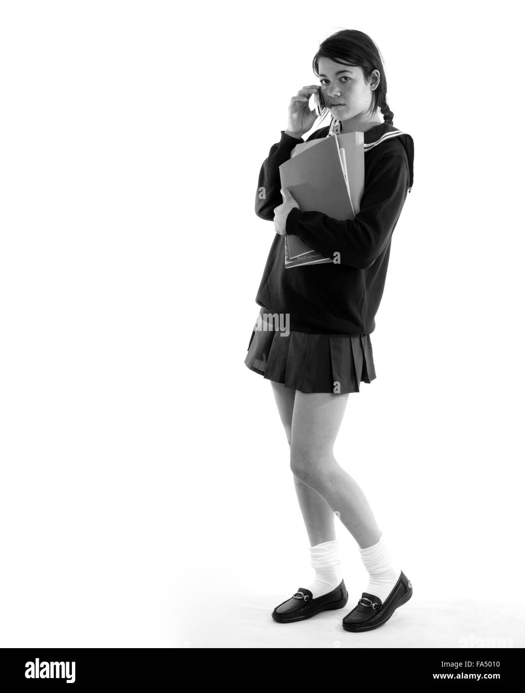 Schoolgirl on her cell phone carrying her school books, wearing a very short miniskirt Stock Photo