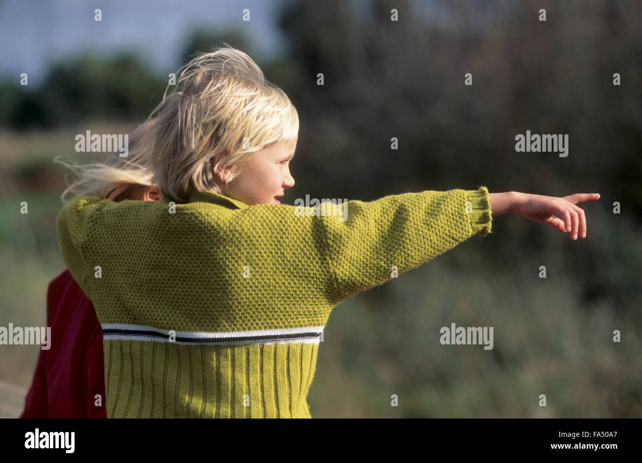 Child with sister pointing to something in the sister. Stock Photo