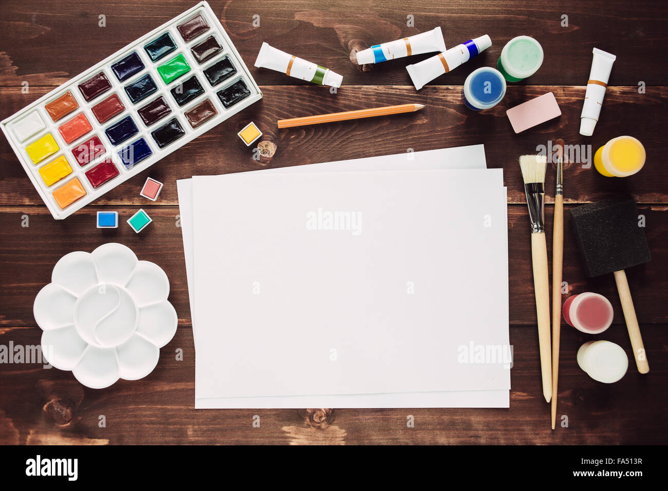 Set of painting equipment with empty paper sheet on wooden table Stock Photo