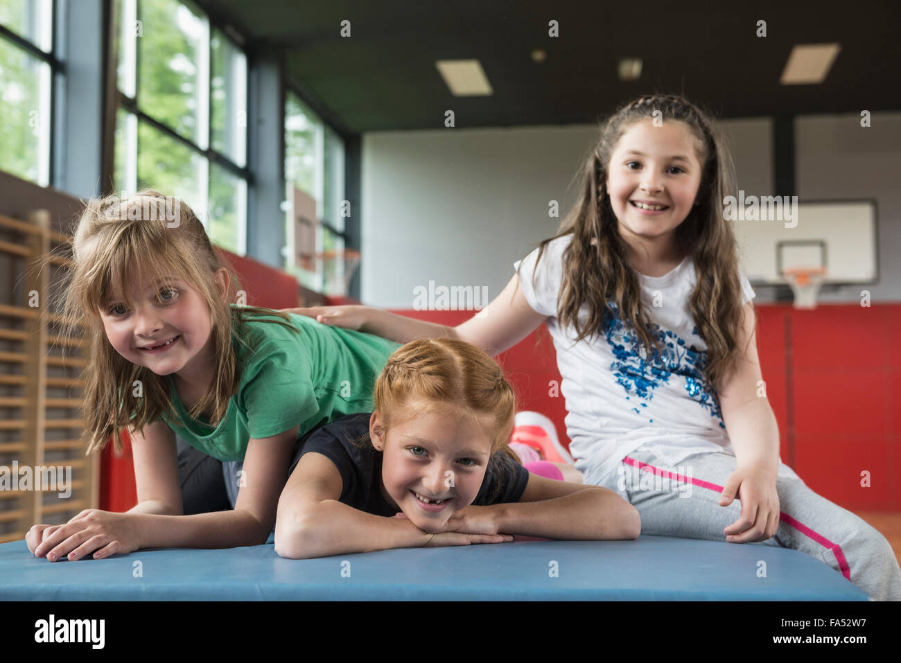 Girls resting on exercise mat in sports hall, Bavaria, Munich, Germany Stock Photo