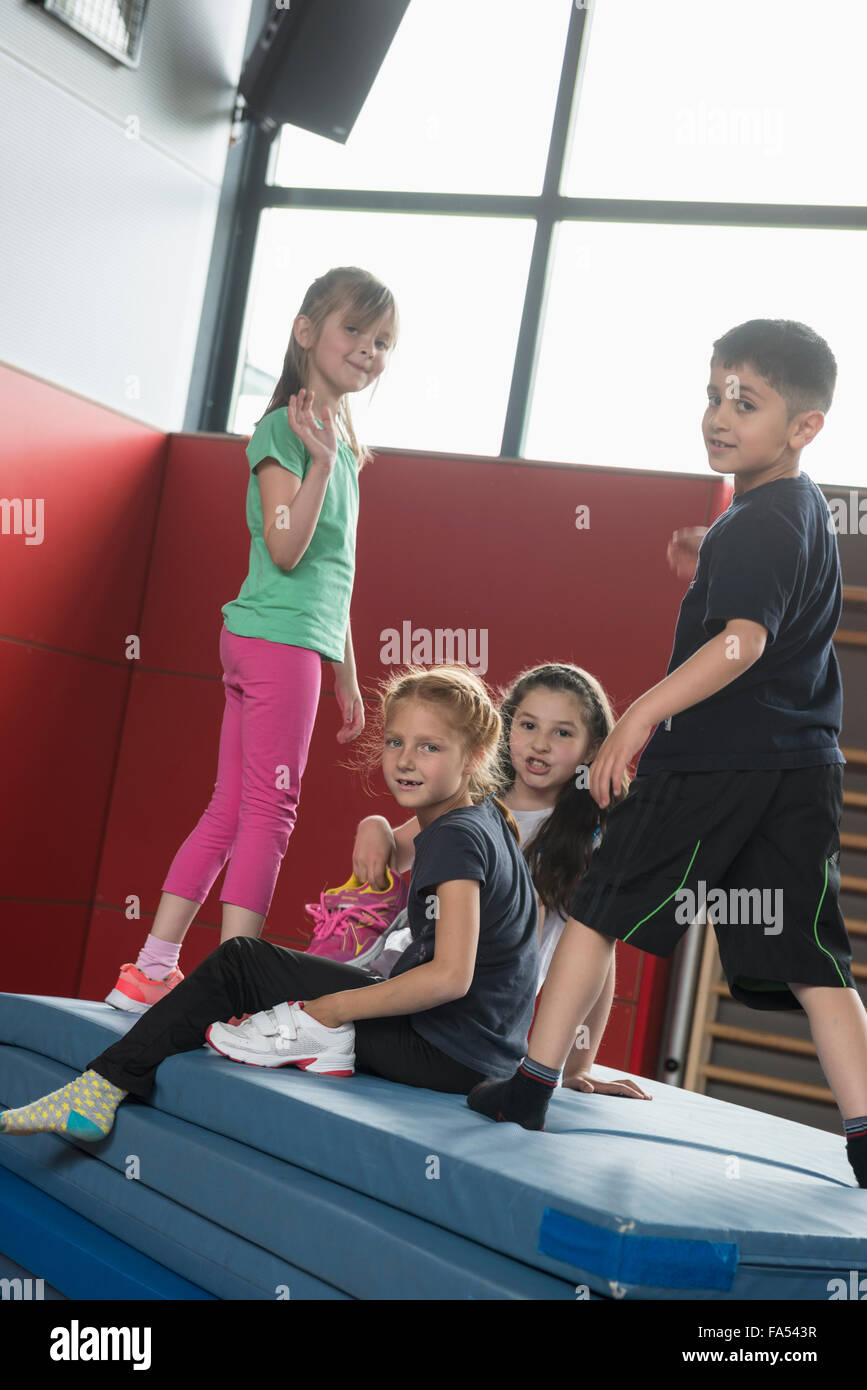Children playing on a pile of sport mats in sports hall, Munich