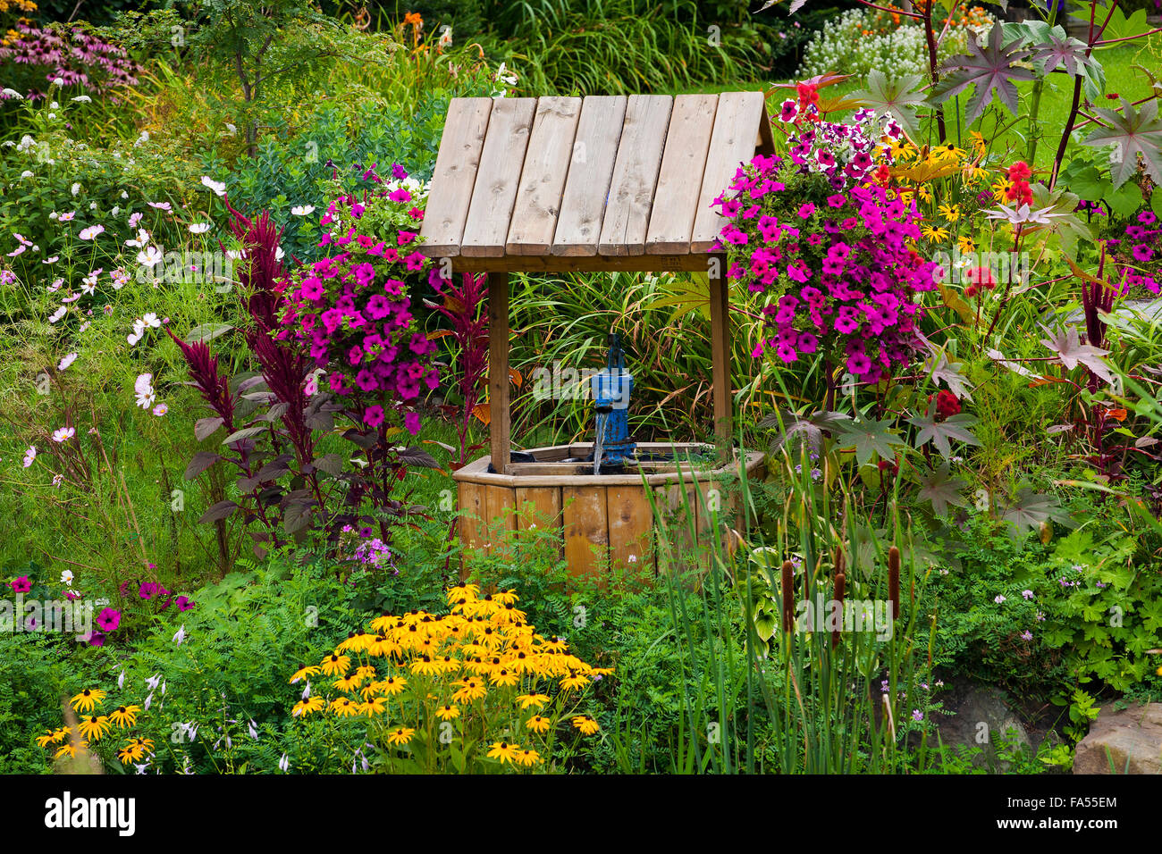 Overgrown garden with flowers and wishing well, Eastern Townships, Granby, Quebec, Canada Stock Photo