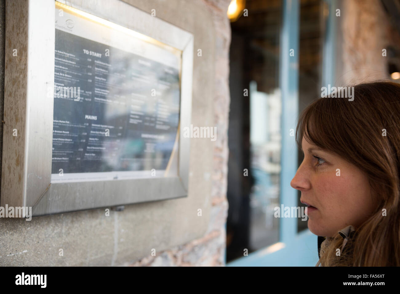 A woman looks at a restaurant menu with disgust Stock Photo