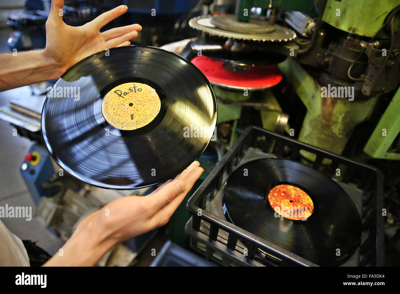Stollberg, Germany. 3rd Dec, 2015. An employee of Celebrate Records checks a freshly pressed record at the pressing plant in Stollberg, Germany, 3 December 2015. According to the Bundesverband Musikindustrie (music industry association), the LP record has been making a comeback for several years. In 2014 around 1.8 million records worth 38 million euros were sold, the most since 1992. At Celebrate Records, around 40 employees produce more than 2 million records each year. Around 70 per cent are exported. PHOTO: JAN WOITAS/DPA/Alamy Live News Stock Photo
