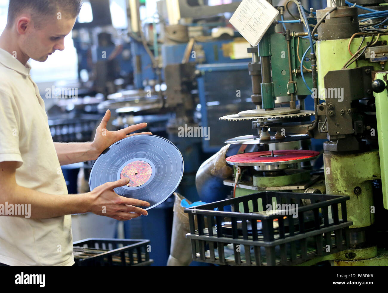 Stollberg, Germany. 3rd Dec, 2015. An employee of Celebrate Records checks a freshly pressed record at the pressing plant in Stollberg, Germany, 3 December 2015. According to the Bundesverband Musikindustrie (music industry association), the LP record has been making a comeback for several years. In 2014 around 1.8 million records worth 38 million euros were sold, the most since 1992. At Celebrate Records, around 40 employees produce more than 2 million records each year. Around 70 per cent are exported. PHOTO: JAN WOITAS/DPA/Alamy Live News Stock Photo