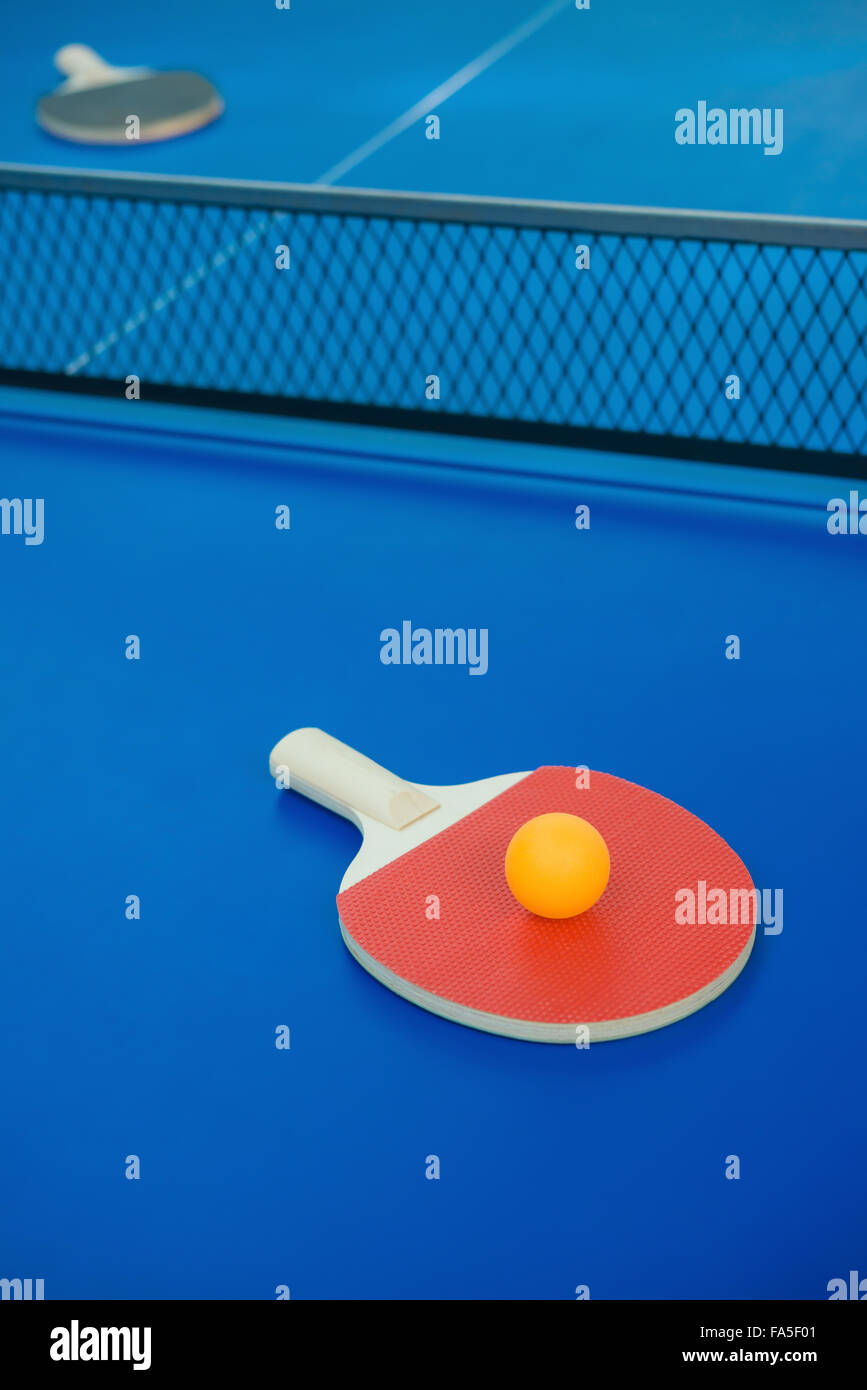 pingpong racket and ball and net on a blue pingpong table vertical Stock Photo