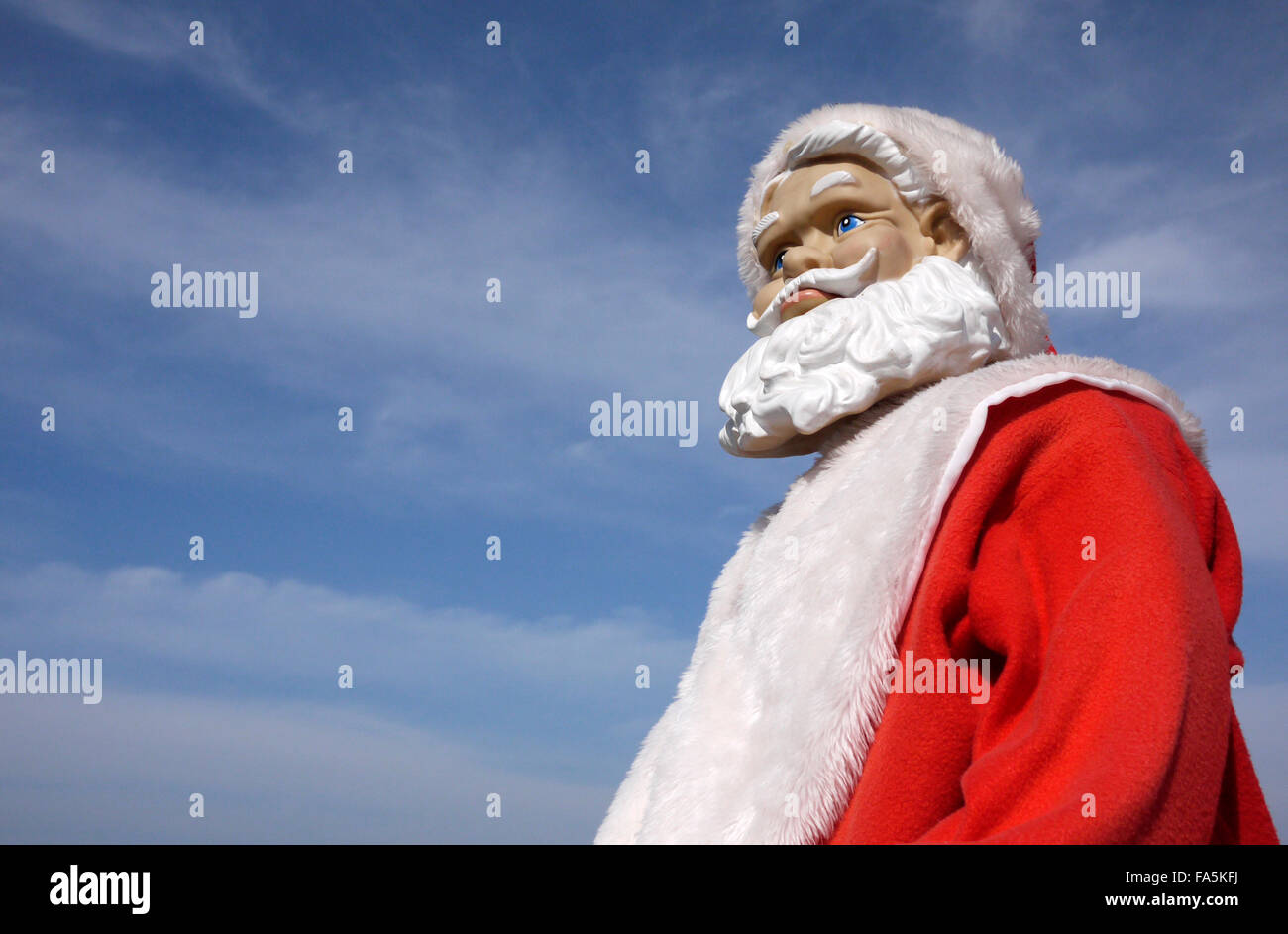 A Santa Claus manikin with a frowning worried apprehensive looking expression pictured outdoors under a blue sky Stock Photo