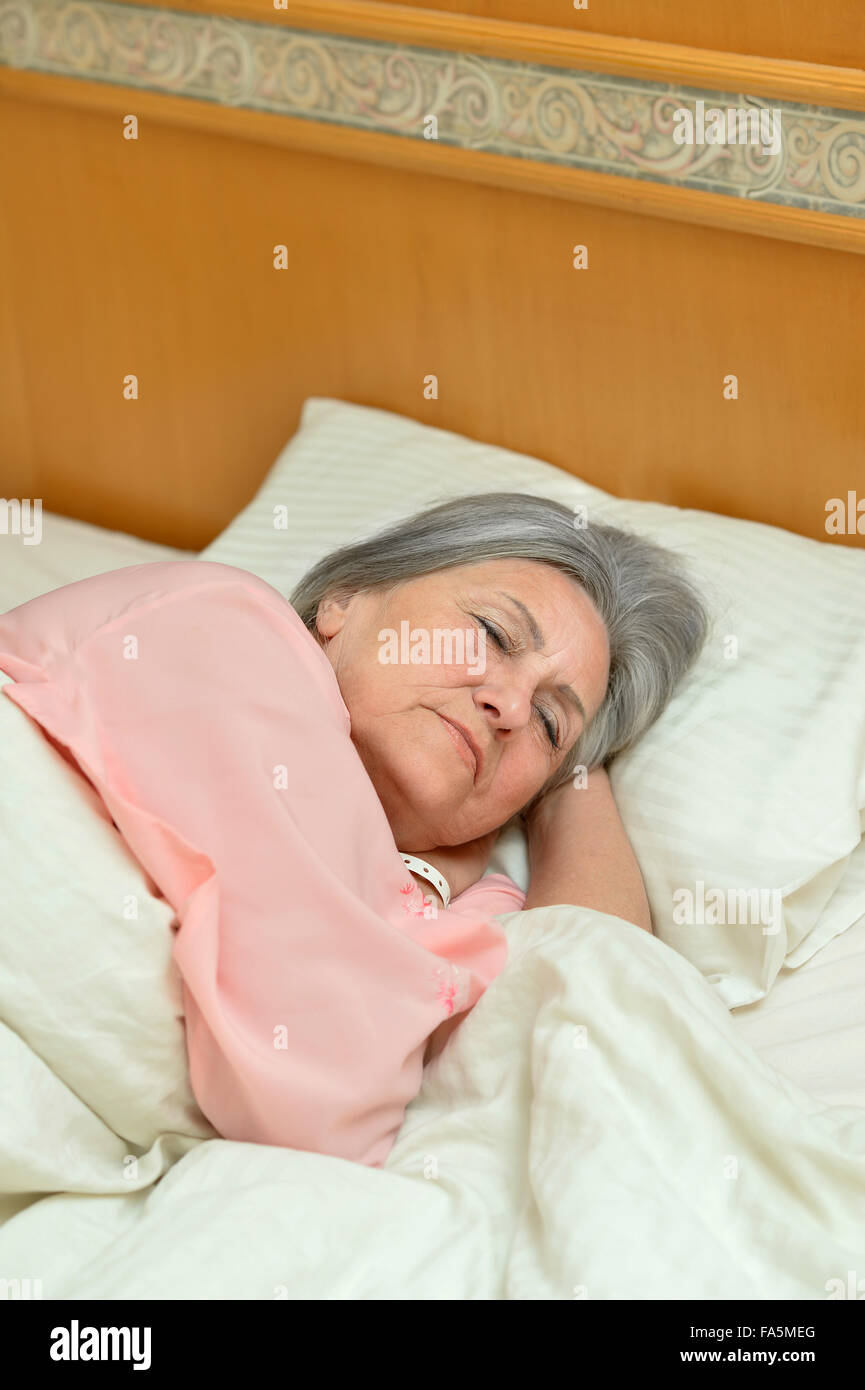 Mature woman sleeping in bed Stock Photo