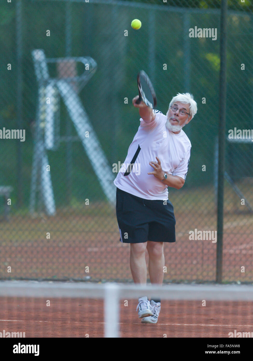 Senior man playing tennis on a gravel court Stock Photo Alamy