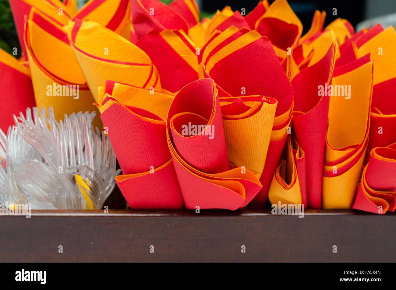 paper napkins with red and orange plastic forks Stock Photo