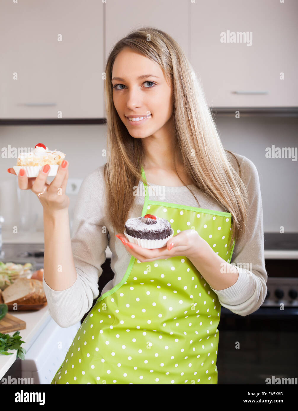 Housewife in apron with cakes in kitchen Stock Photo