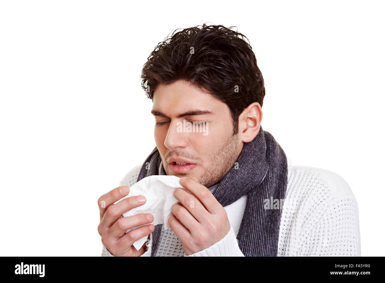 Young man with hay fever sneezing in a tissue Stock Photo