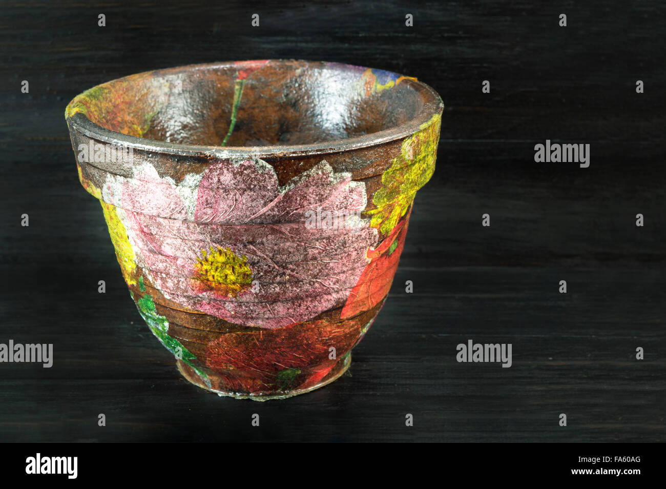 Decoupage decorated flower pot  against black wooden background Stock Photo