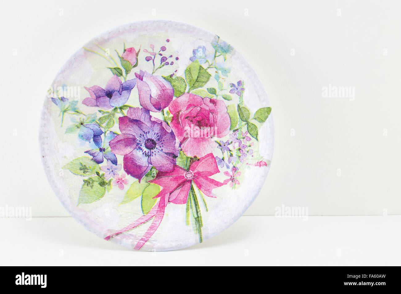 Decoupage decorated plate with flower pattern against white wooden background Stock Photo