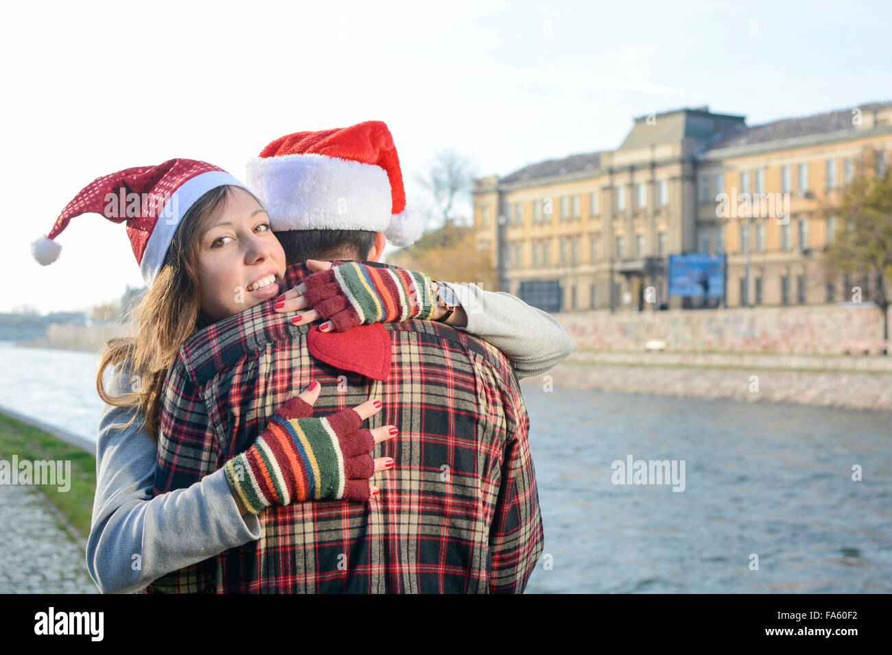 Couple in love hugging outdoors wearing Christmas hats Stock Photo
