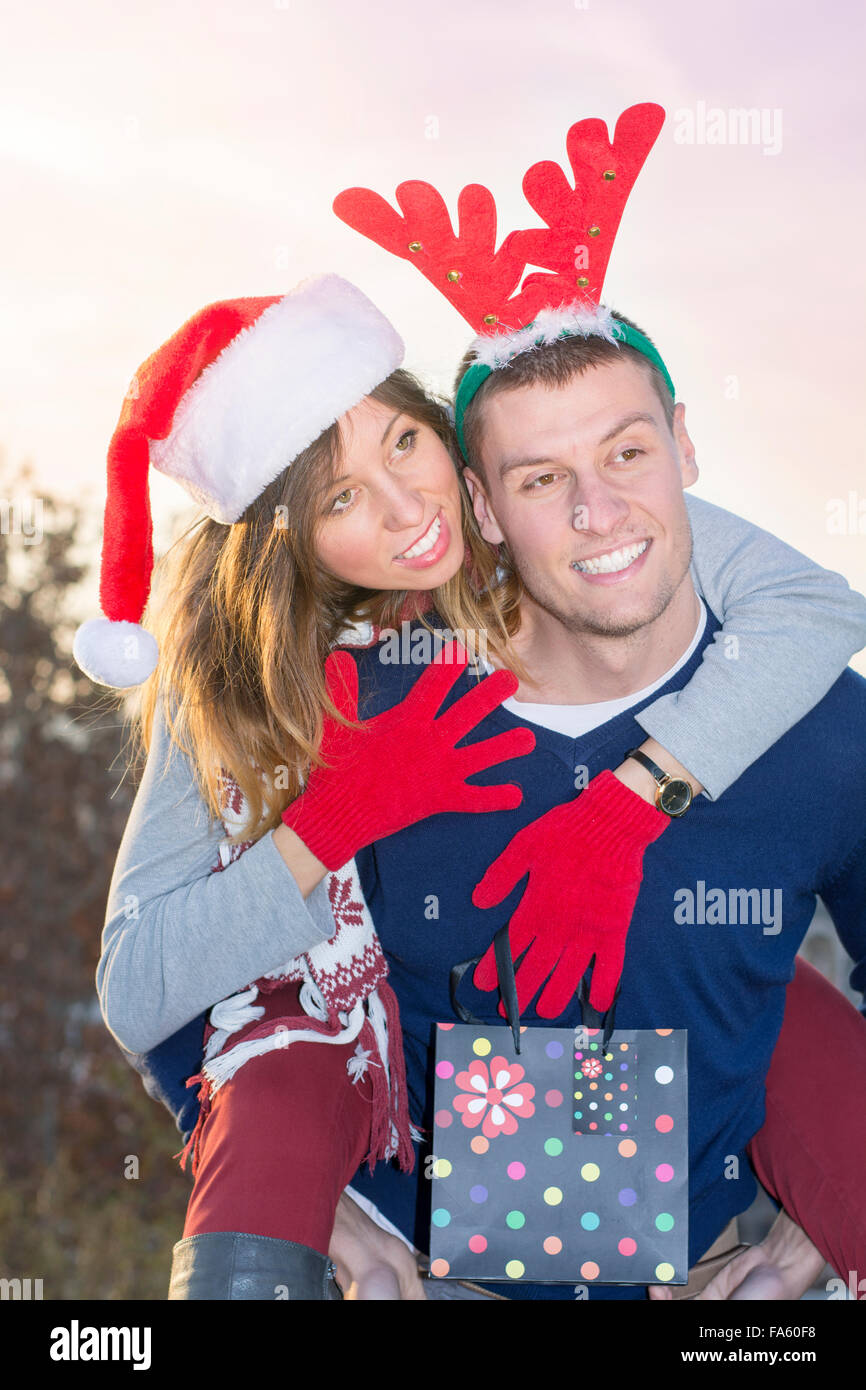 Couple having fun outdoors wearing Christmas holiday hats Stock Photo
