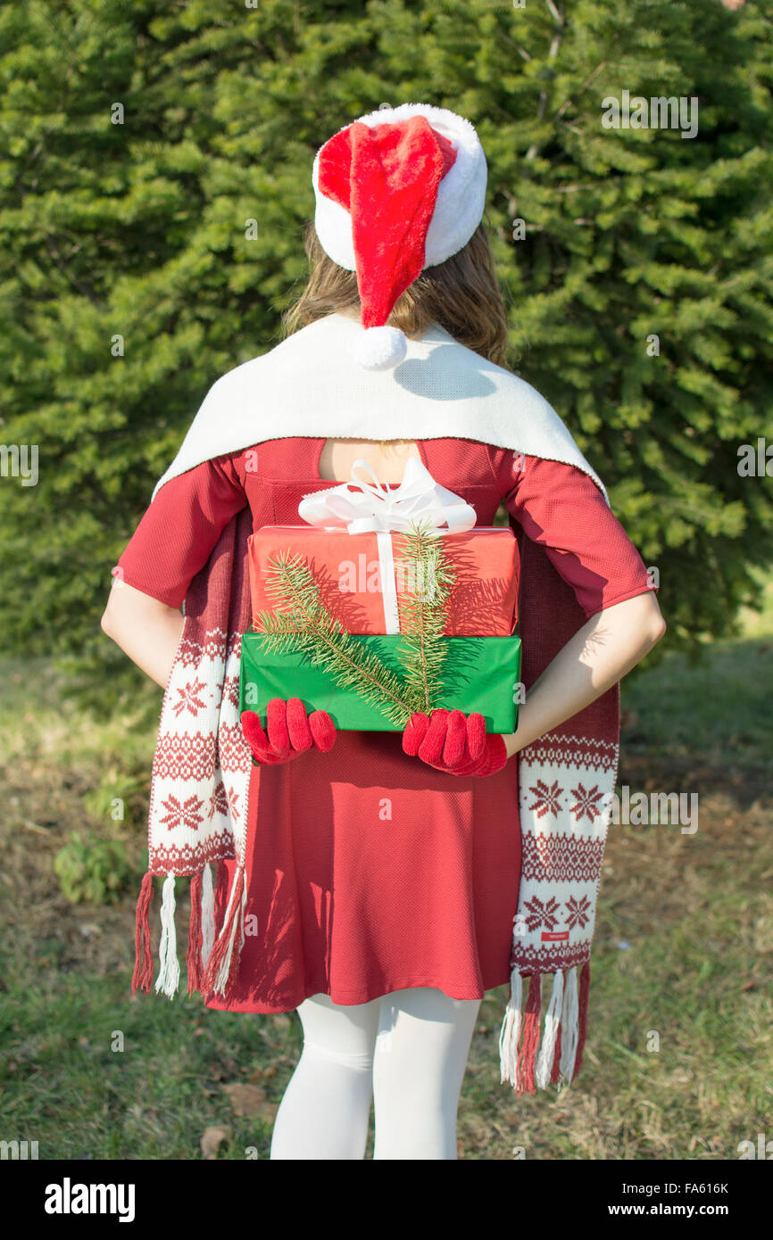 Santa Claus girl hidding  Christmas presents outdoors Stock Photo