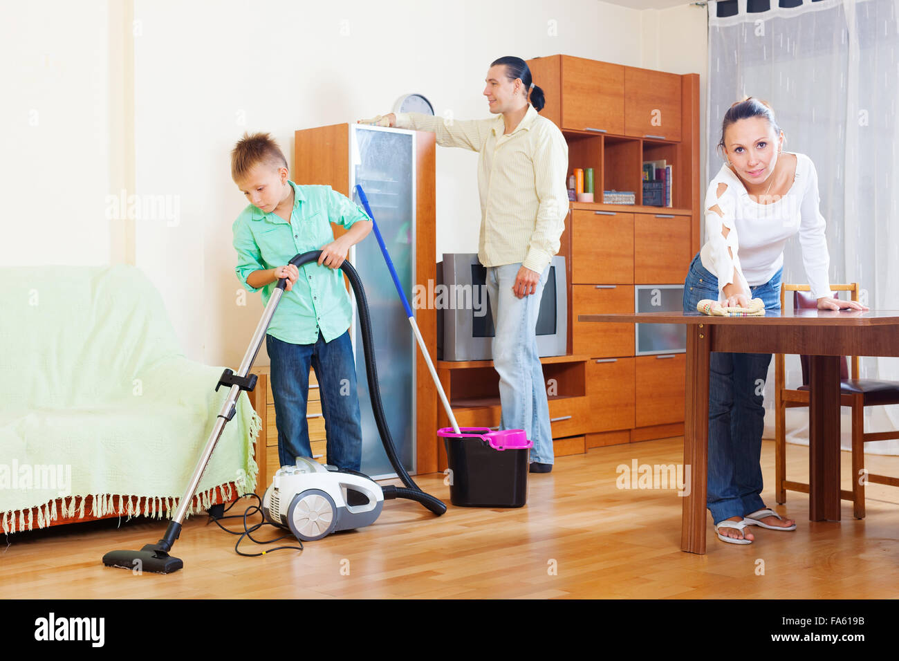 Мама помогла сыну убрать. Семья убирается. Уборка квартиры всей семьей. Уборка в детской комнате. Семья убирается в комнате.