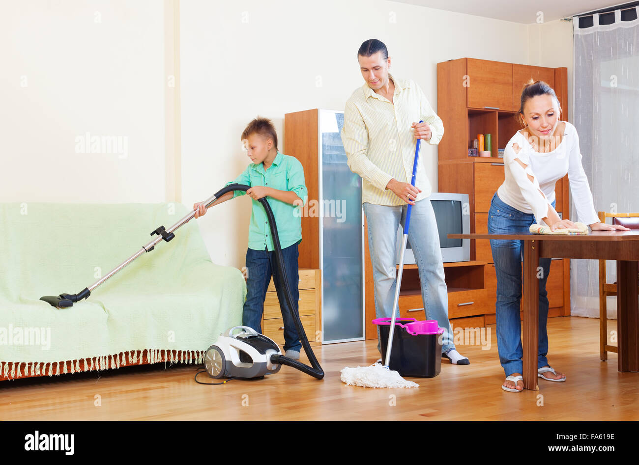 middle-aged couple with teenage son doing house cleaning  in living room at home Stock Photo