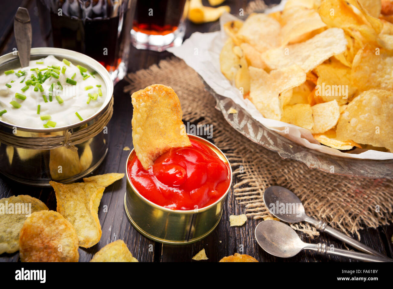 Potato chips with dipping sauces on a rustic table. Stock Photo