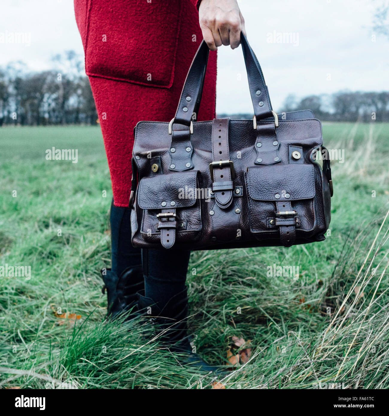 Woman in red overcoat holding a Mulberry Roxanne leather handbag