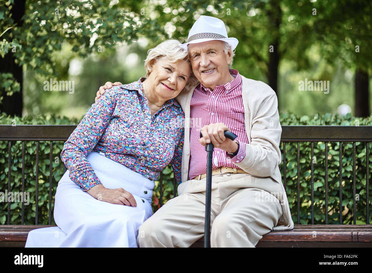 Smiling senior couple sitting on bench in the park Stock Photo - Alamy