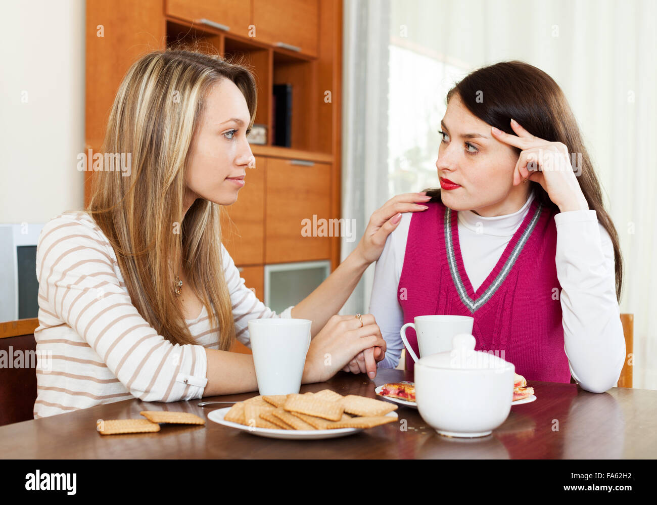 crying brunette woman has problem, girlfriend consoling her at table ...
