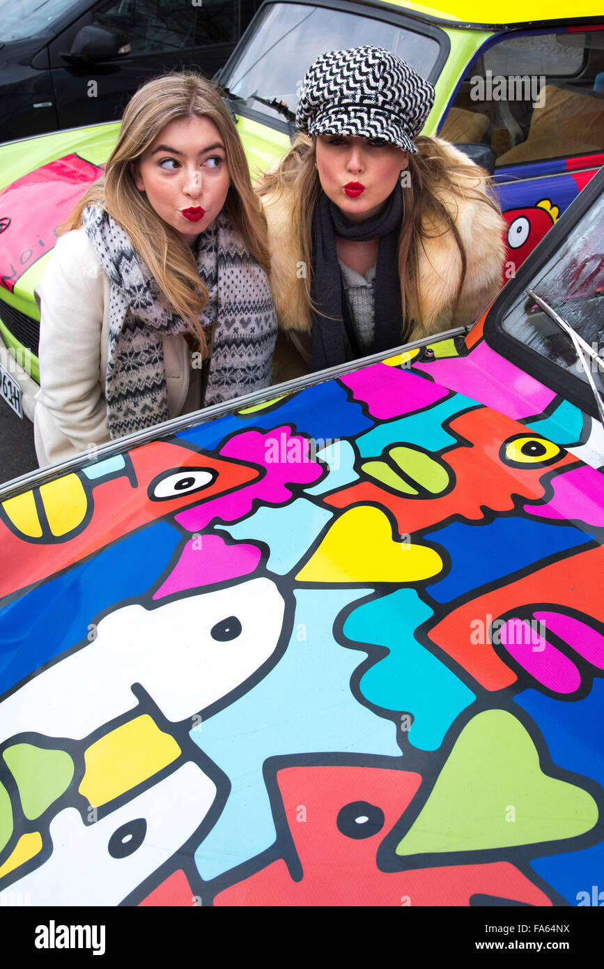 Girls pose at painted car in Berlin Stock Photo