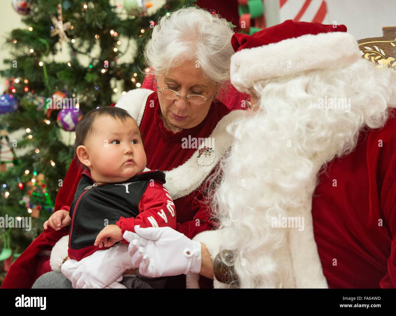Santa Claus sits with Mrs Claus and a Native Alaskan child during a visit to remote villages as part of Operation Santa Claus December 5, 2015 in St. Mary's, Alaska. The program has been held for 59 years and brings Christmas cheer to underserved, remote villages across Alaska. Stock Photo