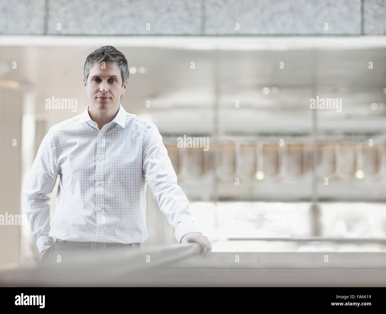 A man in a white shirt with an open collar, in a large airy building. Stock Photo