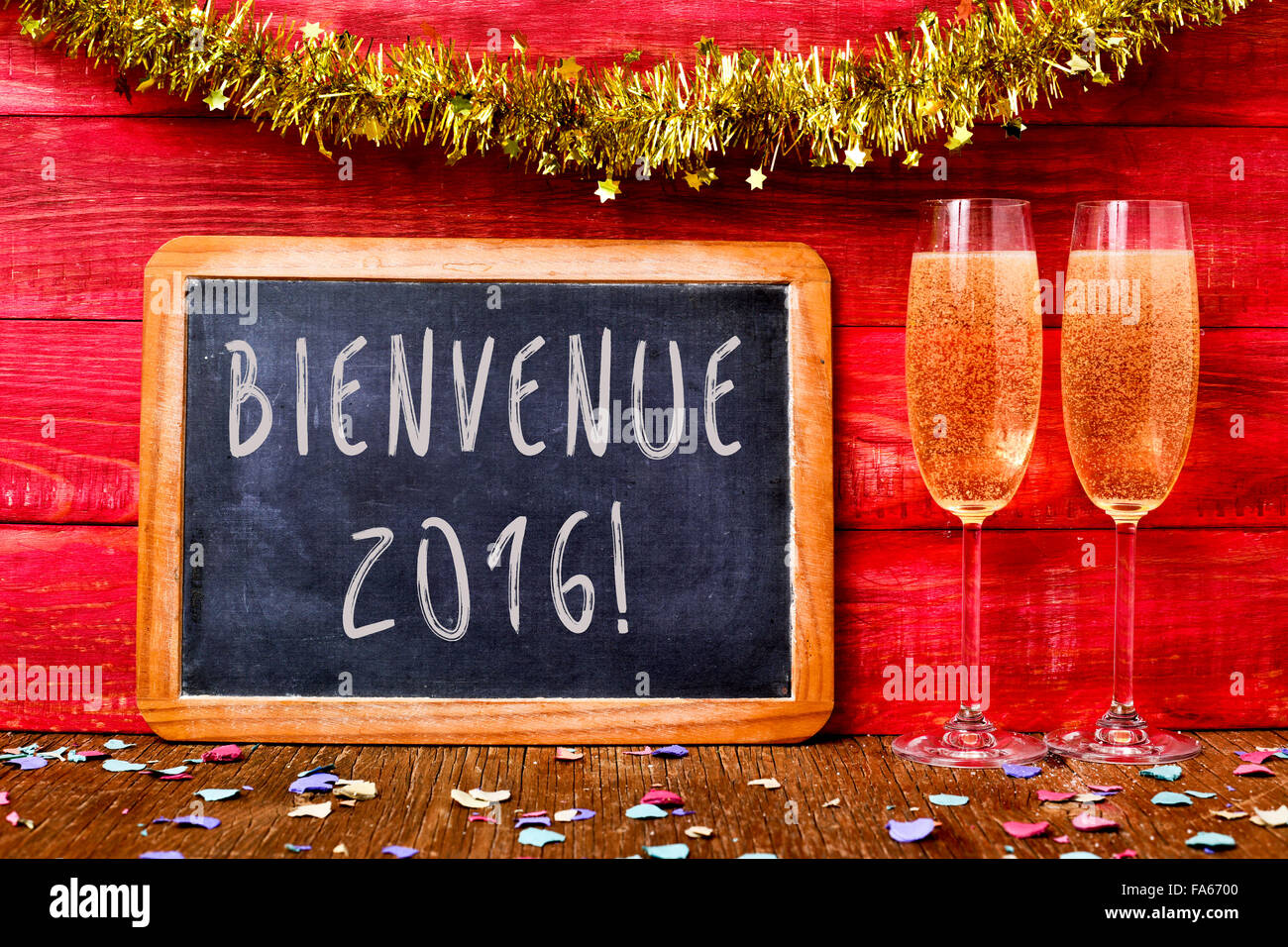 a chalkboard with the text bienvenue 2016, welcome 2016 in french, some confetti and a pair of flute glasses with champagne on a Stock Photo