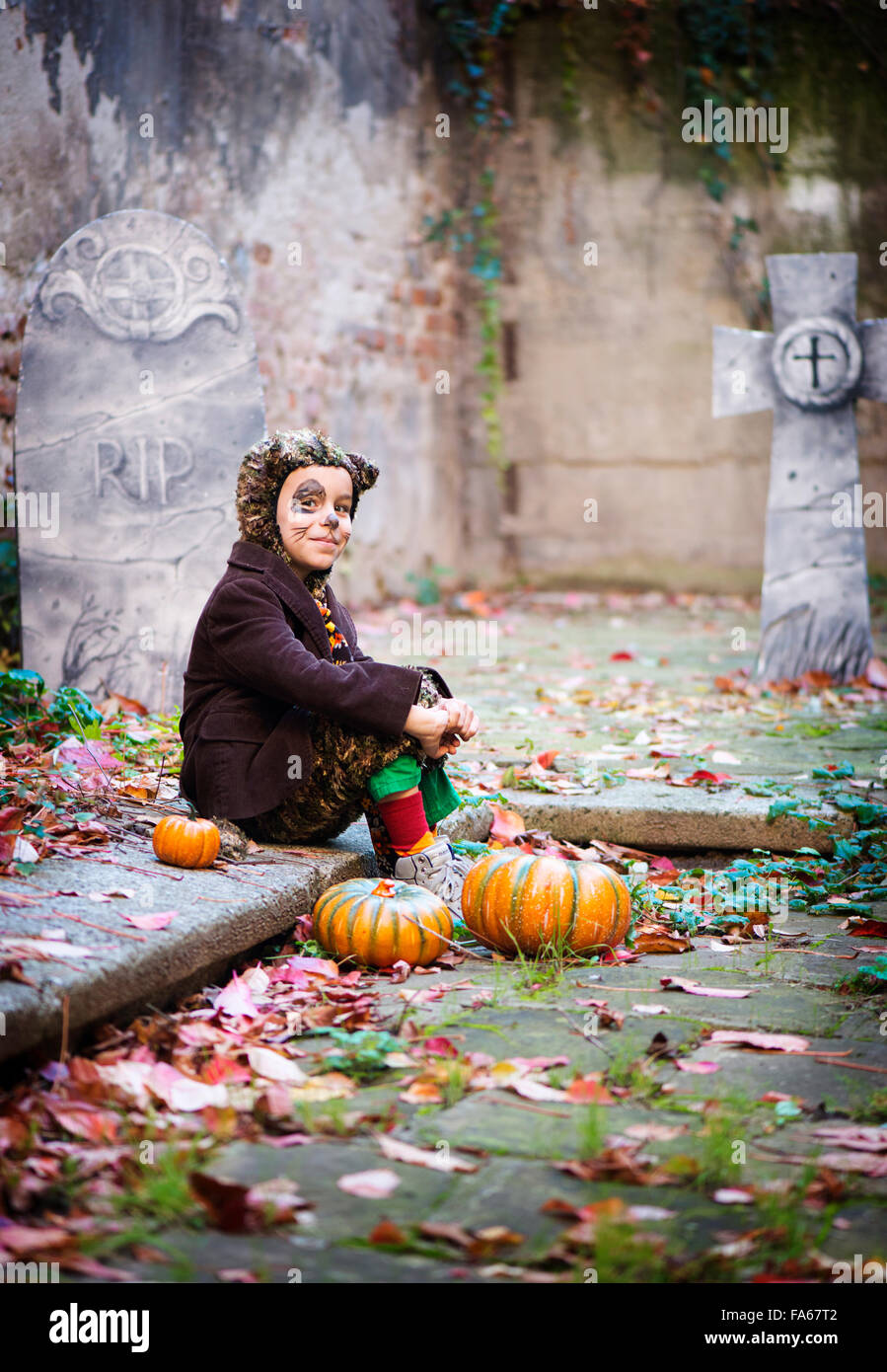 Boy in halloween costume sitting in cemetery Stock Photo