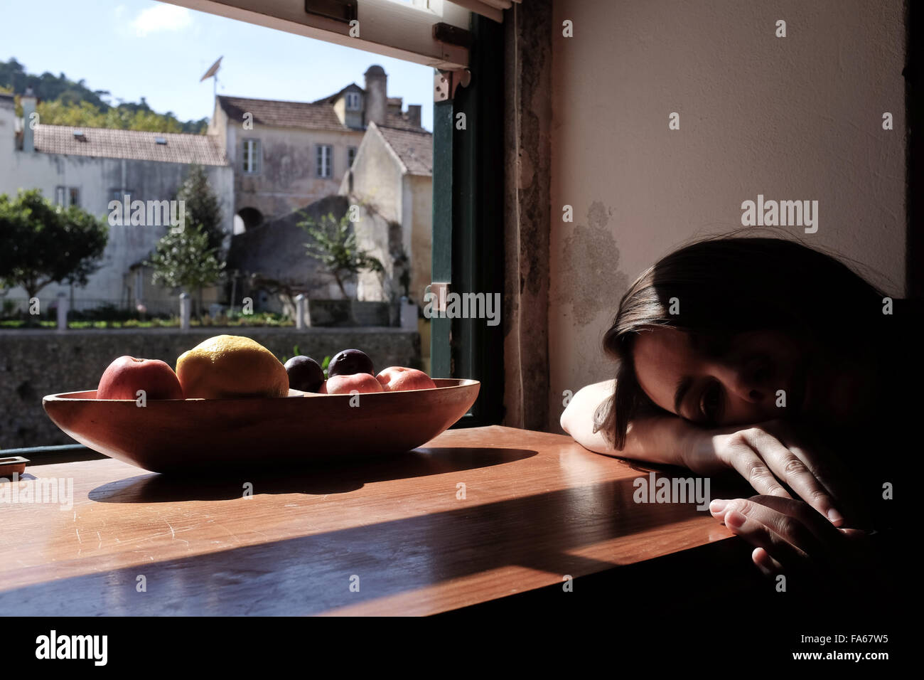 Woman lying down with head on table Stock Photo