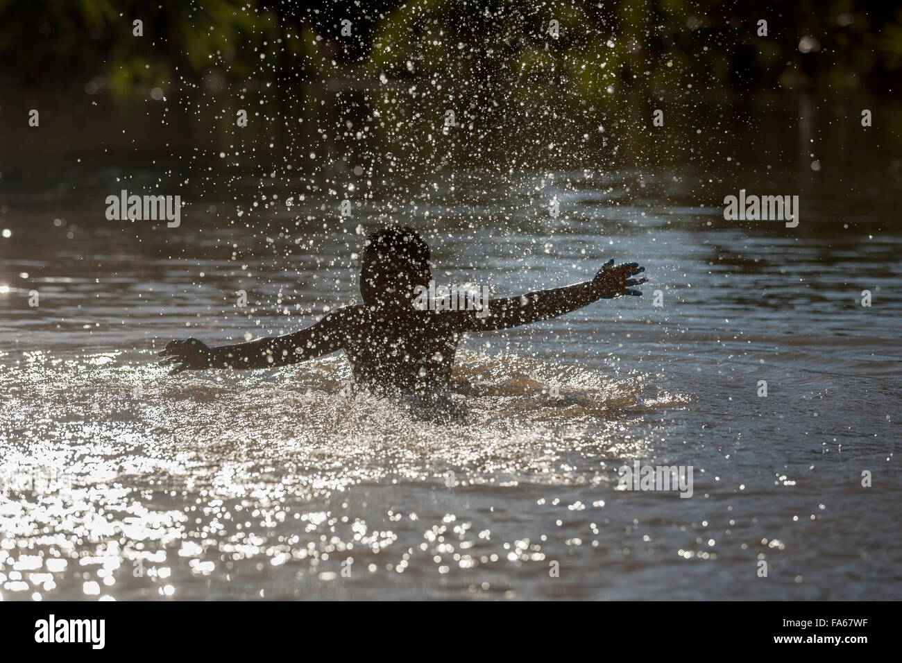 Silhouette of a boy splashing in the river, Thailand Stock Photo