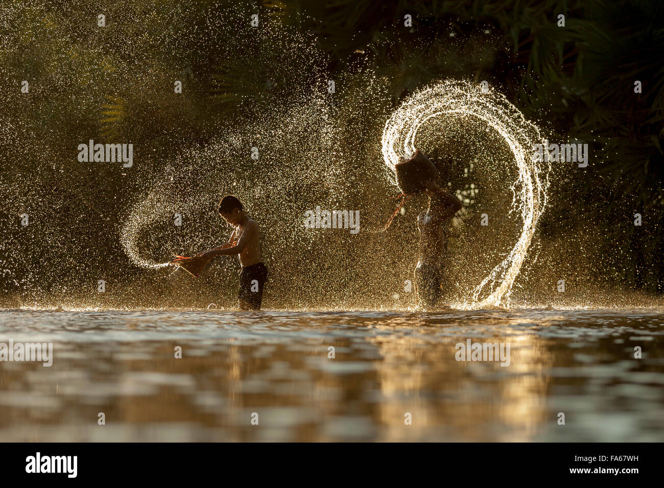 Silhouette of two boys splashing in the river, Thailand Stock Photo
