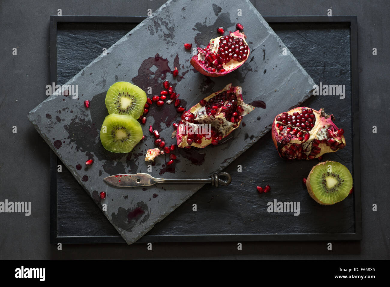 Fresh pomegranate and kiwi on slate in a kitchen Stock Photo