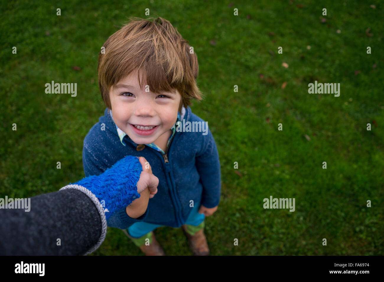 Smiling boy holding mother's hand Stock Photo