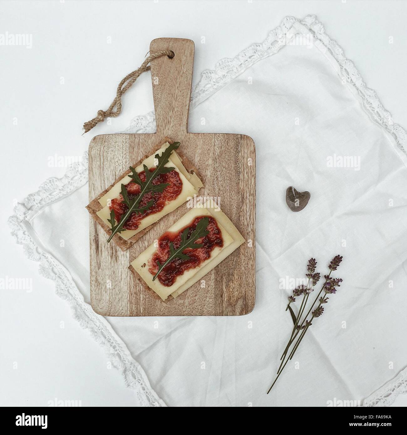 Crispbread with cheese and fig jam on chopping board Stock Photo